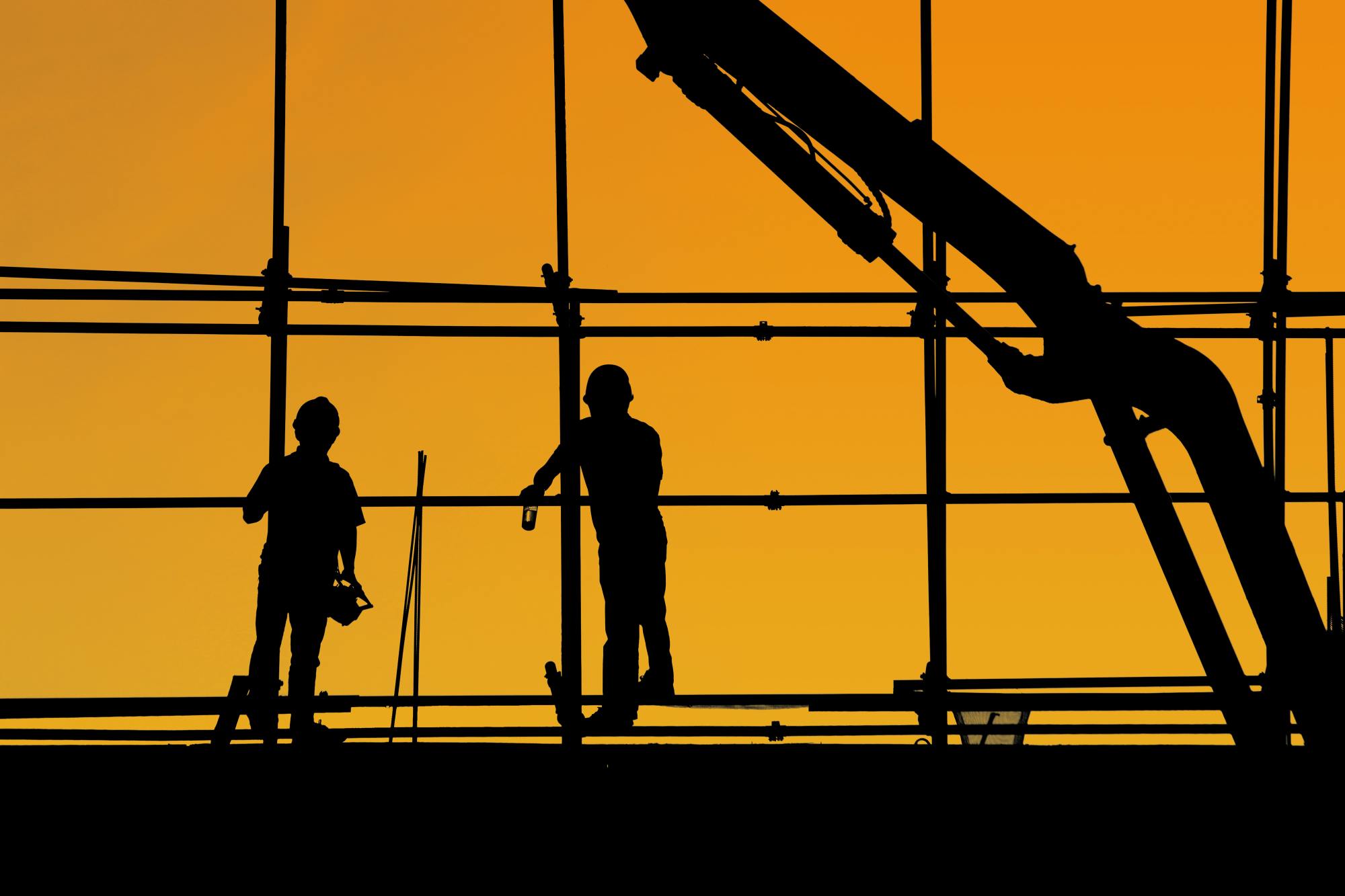 Silhouette of two builders on a building site scaffolding